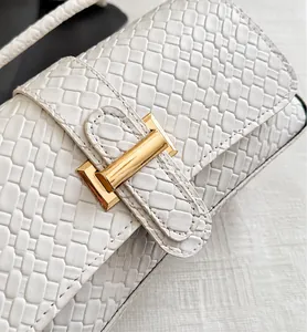 Detalle de la textura tejida y hebilla dorada en el bolso de hombro blanco crema