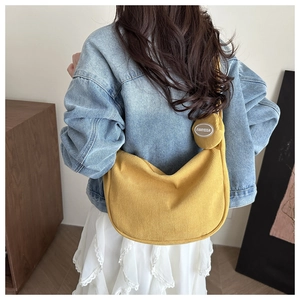 Detail of yellow corduroy crescent bag with small round coin purse on model back