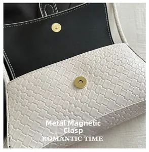 Detalle del bolso de textura trenzada blanca con cierre magnético dorado y forro negro