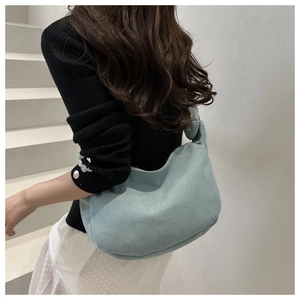 Detail of mint green waffle knit hobo bag showing textured fabric and wide shoulder strap