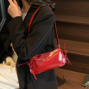 Glossy red faux leather underarm bag with decorative side bows and silver rivet details