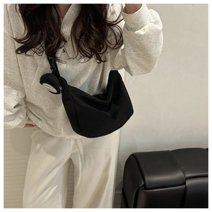 Detail of black corduroy half-moon crossbody bag with detachable round coin purse on side