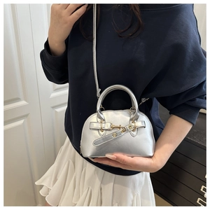 Modella che indossa una mini borsa bowling argento metallizzato con fibbia e tracolla