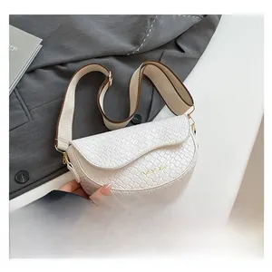Detailed close-up of white woven texture saddle bag with wide woven fabric shoulder strap