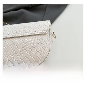 Close-up of beige woven texture and gold D-ring hardware on a stylish saddle bag