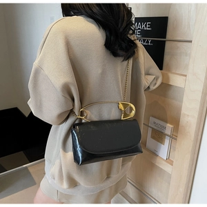 Détail du sac bandoulière noir avec poignée épingle à nourrice dorée et chaîne