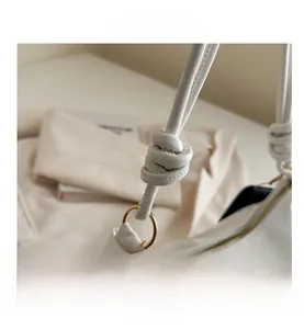 Détail du sac à bandoulière en cuir blanc avec sangle nouée et anneau doré