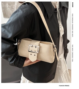 Close-up of beige crocodile pattern faux leather shoulder bag with large metal buckle
