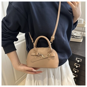 Close-up of shell-shaped handbag with leather strap and metal buckle in beige