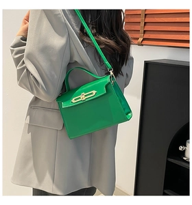 Detailed view of glossy green leather handbag with elegant golden metal clasp detail