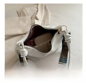 Vue intérieure d'un sac bandoulière en cuir blanc montrant sa grande capacité de rangement