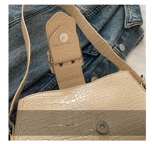 Detail shot of crocodile pattern leather on beige bag with metal magnetic buckle clasp