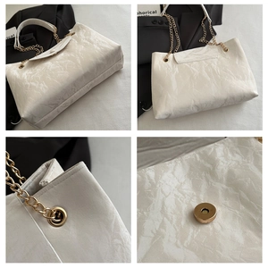Detail of white tote bag with marble texture, gold chain strap and magnetic closure