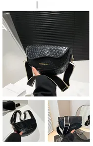 Detail of black PU leather saddle bag featuring woven texture and striped wide shoulder strap