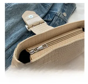 Detail of smooth metal zipper on beige crocodile embossed faux leather shoulder bag