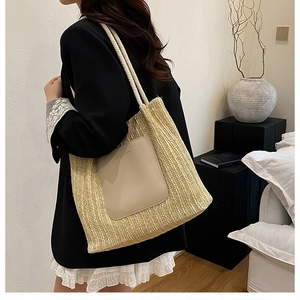 Detail of a large woven tote bag with white rope handles and a beige leather patch