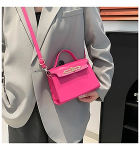 Detailed close-up of a pink structured handbag featuring a gold metallic lock and top handle