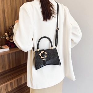 Borsa a mano nera con glitter, chiusura a fiore dorato e design a base curva