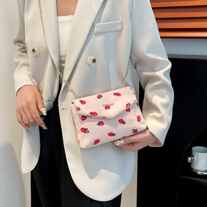 Pink corduroy crossbody bag with strawberry print and gold chain strap on model