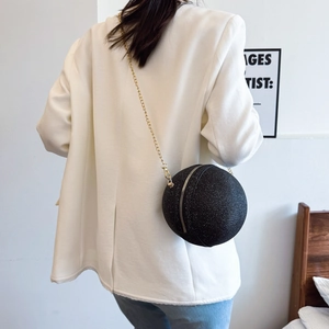 Elegante borsa da sera sferica nera con catena dorata indossata su blazer bianco