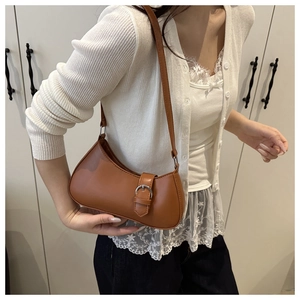 Nahaufnahme einer braunen PU-Leder-Schultertasche mit Schnalle, getragen von einem Model