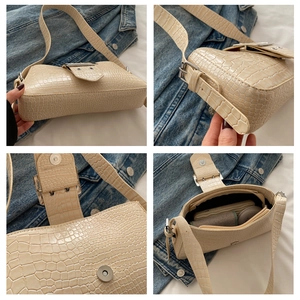 Detail view of beige croc-embossed bag with silver hardware and interior compartments