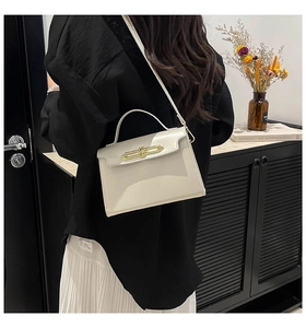 Detail of elegant beige crossbody bag with gold buckle on a model in modern interior
