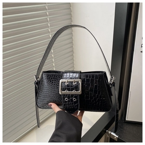 Detail view of glossy black crocodile-patterned leather and large silver metal buckle