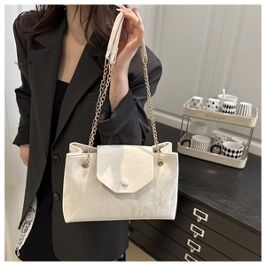 Detail of white textured leather shoulder bag with gold chain and circular clasp
