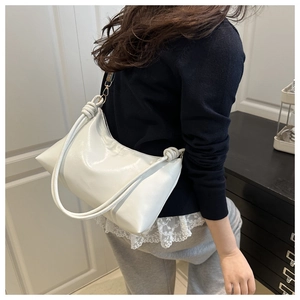 Détail du sac sous le bras blanc brillant montrant le nœud de bandoulière unique