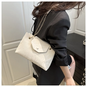 Détail du sac à bandoulière blanc plissé avec chaîne dorée et fermeture à bouton rond