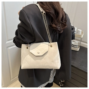 Gros plan d'un sac porté épaule en cuir crème avec chaîne dorée sur un mannequin