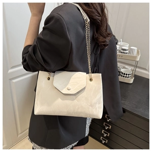 Sac à bandoulière chic en cuir crème avec chaîne dorée porté par un mannequin de dos