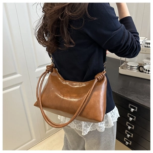 Close-up of brown retro hobo bag featuring artistic knotted strap and oily leather texture