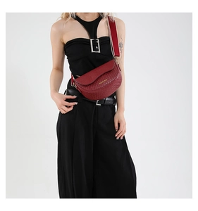 Detail of red woven leather saddle bag with striped strap and gold buckle