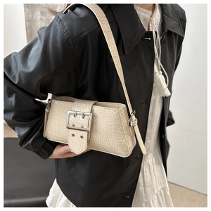 Detail of cream crocodile embossed underarm bag with silver buckle on black jacket