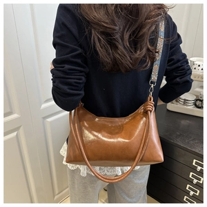 Detail of a brown leather shoulder bag with knotted decor and a vintage floral woven strap