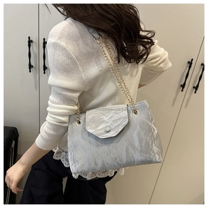 Détail du sac bandoulière gris argenté avec texture plissée et chaîne dorée chic