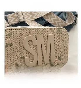 Dettaglio mini borsa in paglia intrecciata con ricamo SM e motivi floreali