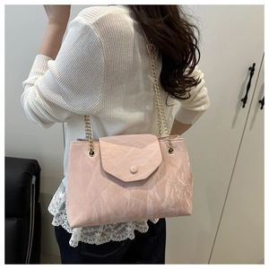 Detail of light pink shoulder bag with pleated texture and golden chain strap