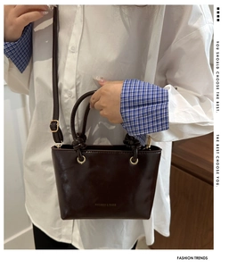 Dettaglio borsa tote in pelle lucida marrone scuro con inserti dorati e tracolla