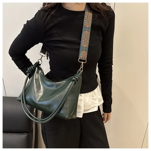Detail of dark green patent leather tote bag with vibrant ethnic style woven strap