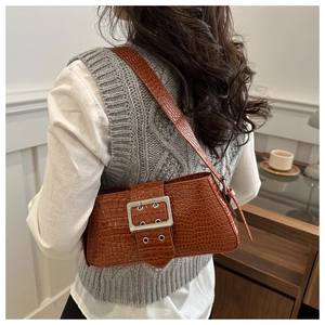 Detail of vintage brown crocodile texture shoulder bag with silver buckle worn by a model