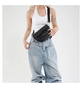 Detail of black crocodile texture saddle bag with fashion brand logo and wide strap