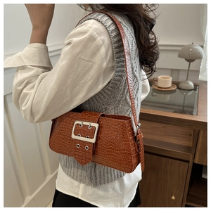 Detailed view of a brown crocodile pattern shoulder bag with a large silver buckle
