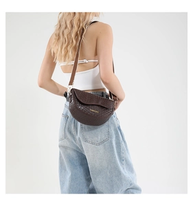 Detail of dark brown crescent bag with woven texture and adjustable wide shoulder strap