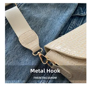 Macro shot of gold metal hook and buckle on a crocodile pattern saddle bag strap