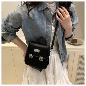 Classic black leather crossbody satchel with silver hardware shown in a lifestyle setting