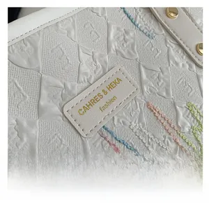 Détail macro du tissu blanc texturé avec écusson de marque et coutures décoratives colorées