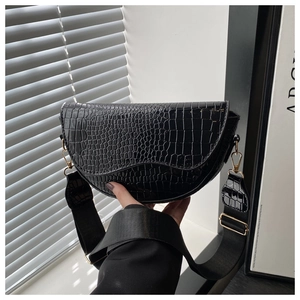 Close-up of black crocodile pattern saddle bag with gold metal hardware and wide strap